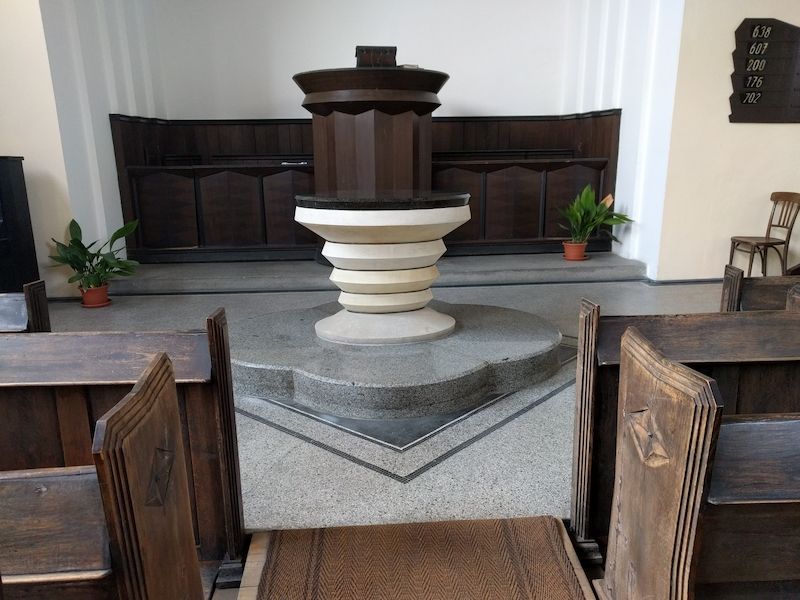 Přirozenou dominantou kostela je tmavohnědá dřevěná kazatelna a před ní stojící kamenný stůl Páně.
