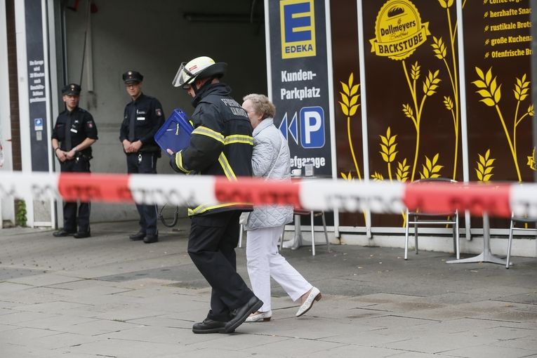 Německý hasič odvádí v Hamburku starší ženu od supermarketu, kde úročník pobodal několik lidí.