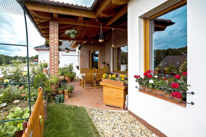 Pokud to počasí dovolí, může si rodina užívat díky posezení na zastřešené terase krásné prostředí zahrady. Ve spodní partii okna si všimněte ručně kované dekorativní mřížky pro květinové truhlíky.