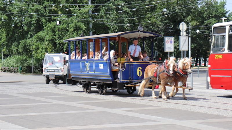 Na Moravské náměstí vjíždí tramvaj tažená koni a v těsném závěsu ji následuje multikára úklidové firmy připravená sbírat případné koňské koblížky