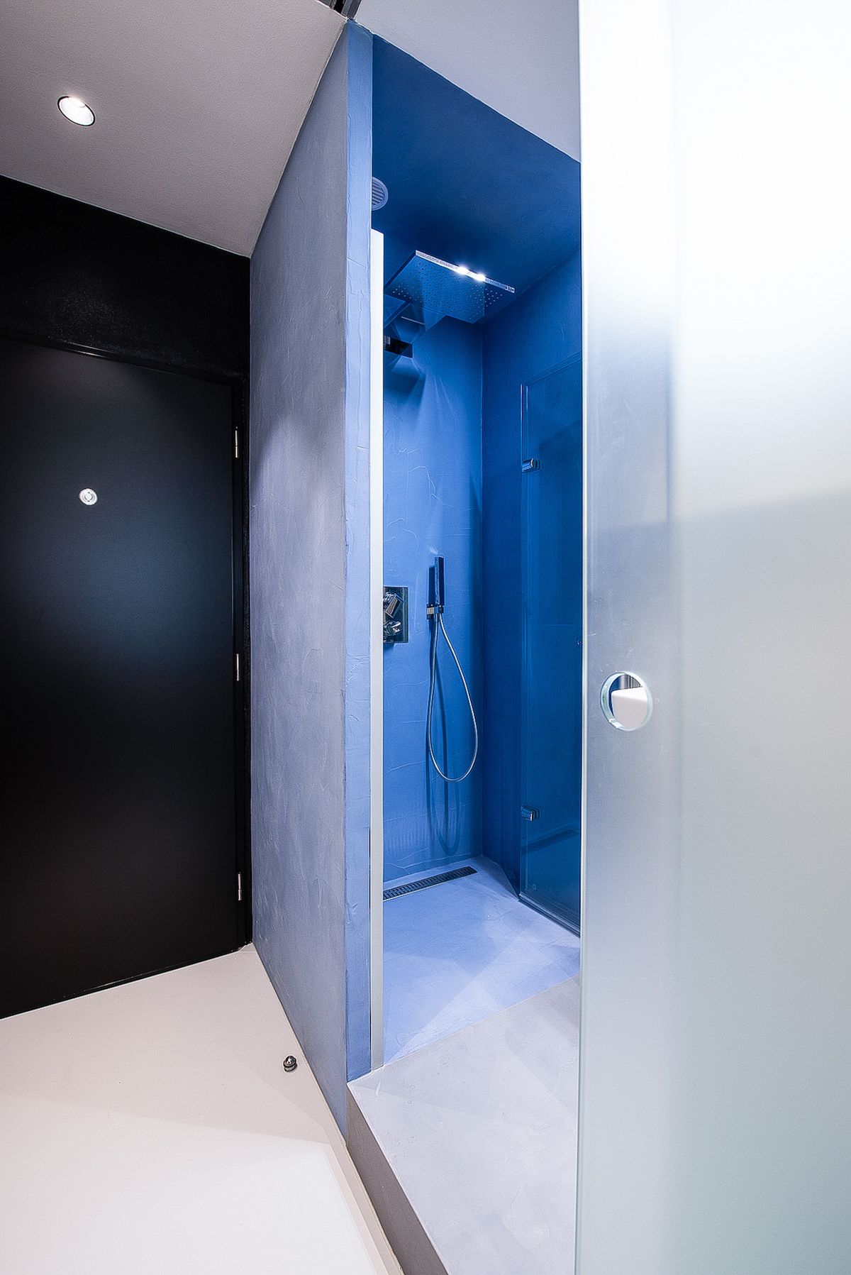 Modrá stěrka pokračuje do koupelny, respektive do sprchového koutu, kde ji najdeme na stěnách, podlaze i stropu.