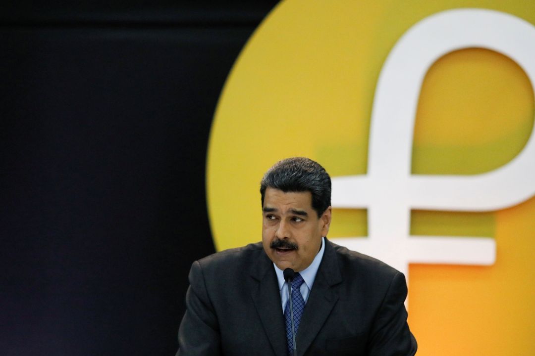 Venezuelský prezident Nicolás Maduro, na pozadí je logo kybernetické měny petro.
