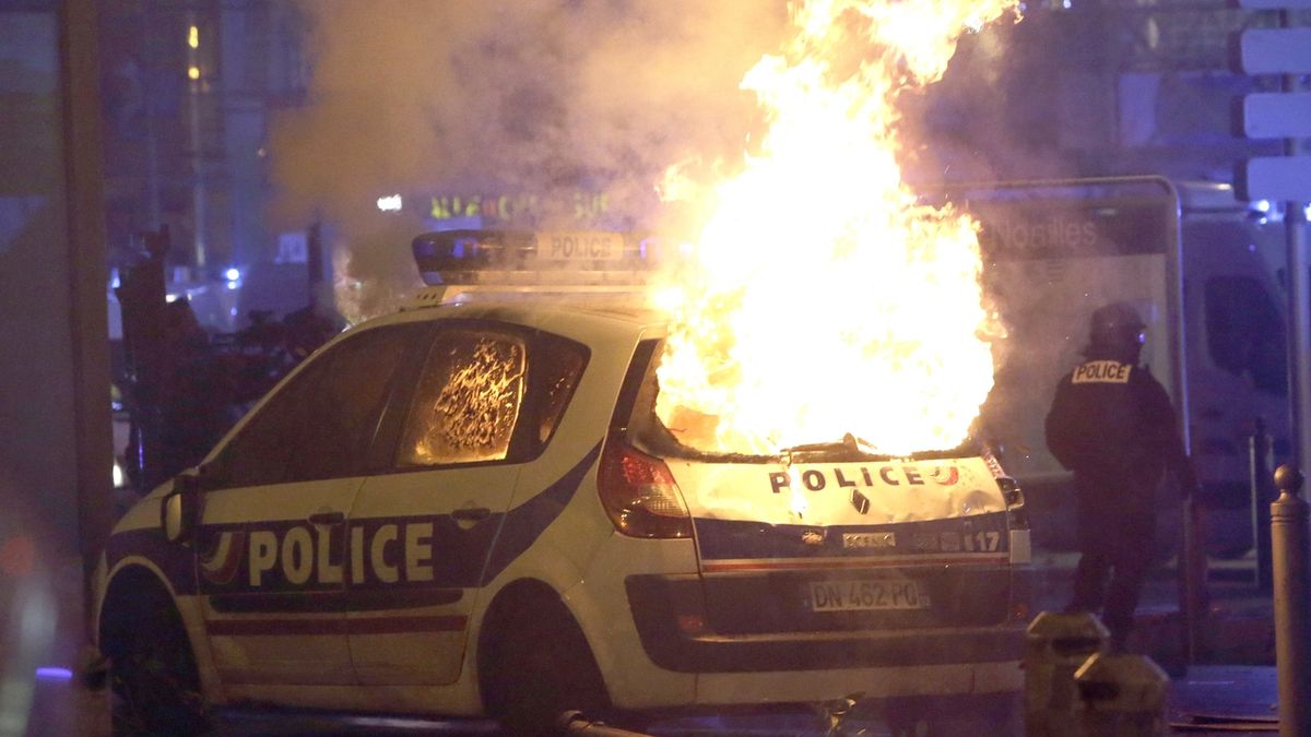 Hořící policejní auto při násilných protestech v Paříži