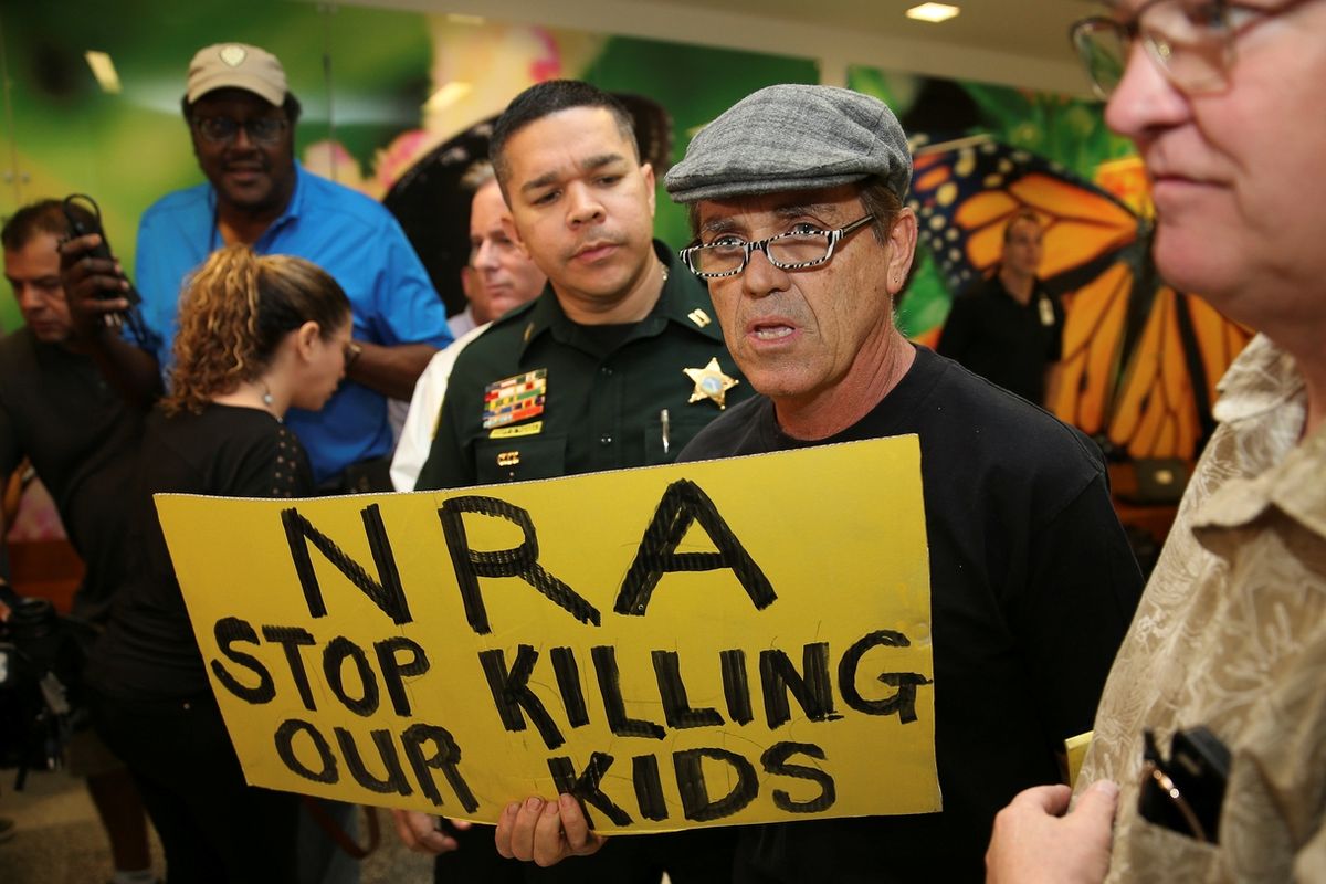 Lidé před soudem, kde stanul útočník z floridské střední školy Nikolas Cruz, protestují proti vlivné organizaci NRA, která zastupuje zájmy výrobců zbraní a hájí jejich volný prodej. Cruz poloautomatickou pušku AR-15 koupil legálně.