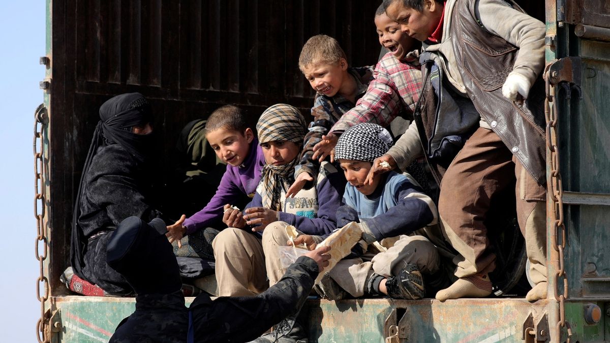 Milicionář Syrských demokratickýh sil dává chleba dětam v koloně aut z Islámského státu. 