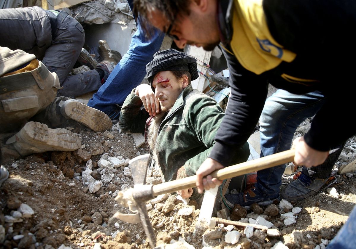 Záchranáři osvobozují muže z hromady sutin, ve které uvíznul poté, co nálet poškodil dům ve čtvrti Ghouta v syrském Damašku.