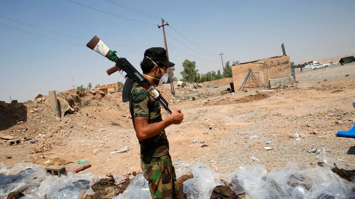 Příslušník šíitské milice u vykopaných těl obětí Islámského státu u Sulajmánije 
