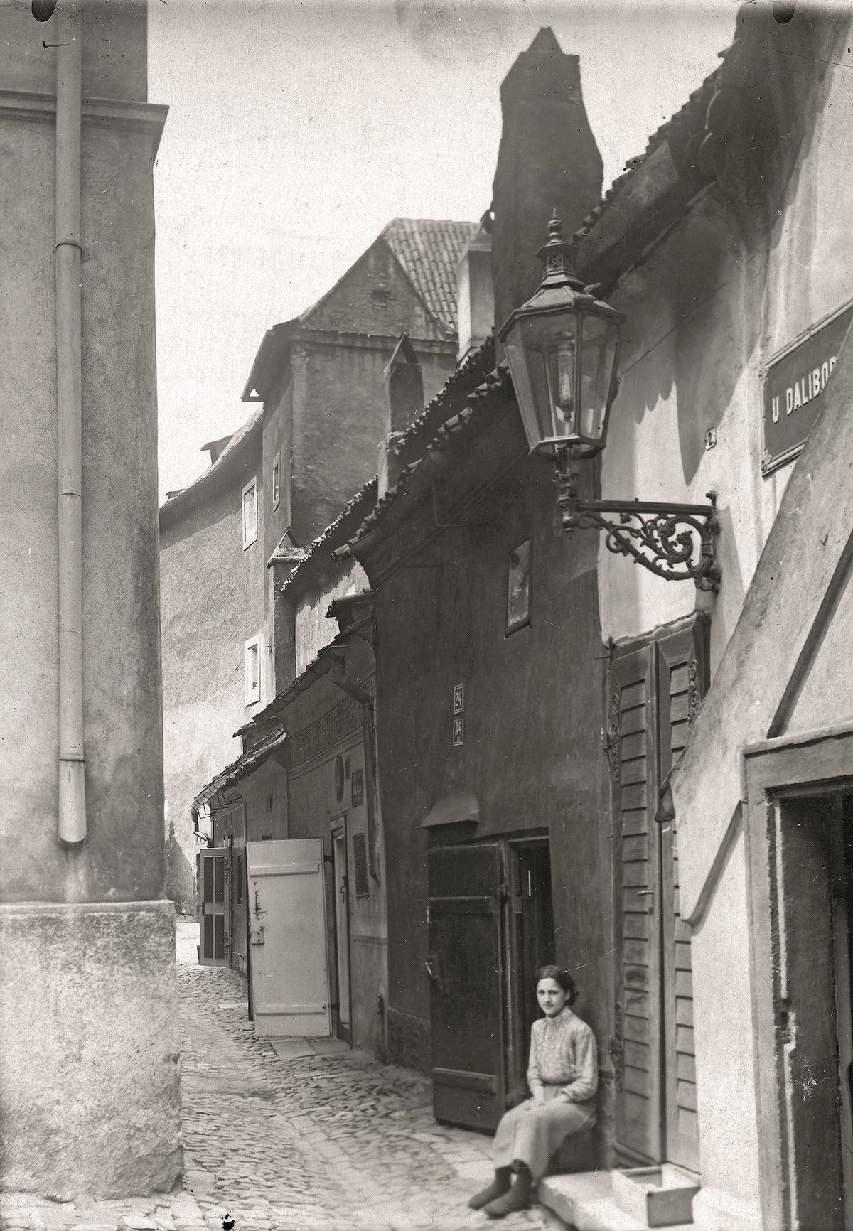 Jedna z obyvatelek Zlaté uličky odpočívá na zápraží v roce 1926.