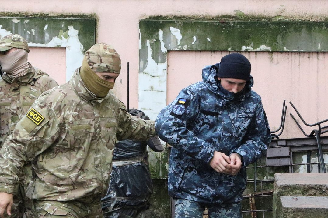 Příslušník ruské tajné služby FSB odvání zadrženého ukrajinské námořníka k soudu. 