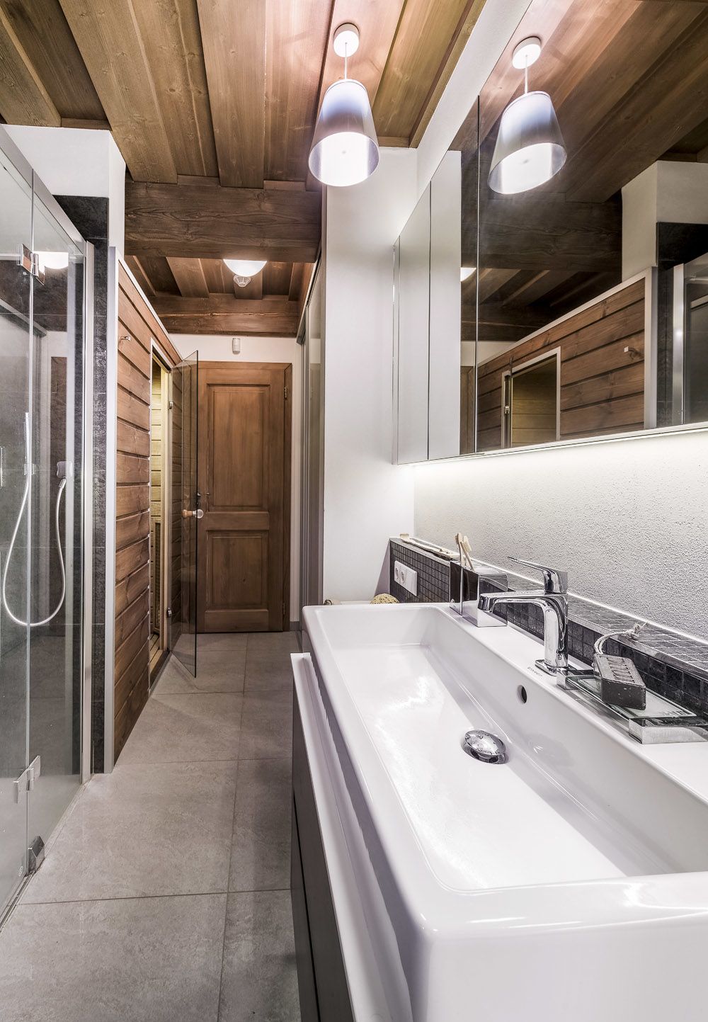 Koupelna v přízemí zahrnuje také infrasaunu, klozet (Duravit) a skříň s úložným prostorem. Je vybavena prostorným sprchovým koutem s parním panelem (Artwegwer) a velkým umyvadlem Vero (Duravit) se stojánkovou baterií (Palazzani).
