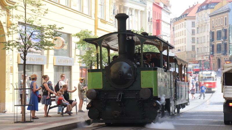 Parní tramvaj Karolína s vlečným vozem plně obsazeným cestujícími odjíždí z náměstí Svobody na svoji okružní jízdu.