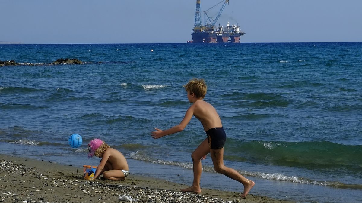 Děti si hrají u přístavu Larnaka na Kypru s těžařskou plošinou v pozadí (ilustrační foto)