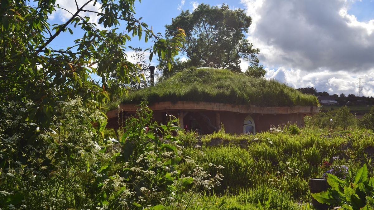 Domek má trávou porostlou střechu.