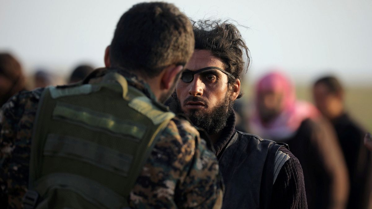 Bojovník Arabsko-kurdské milice (SDF) kontroluje muže u vesnice Baghúz, kde zuří poslední boje s radikály Islámského státu.