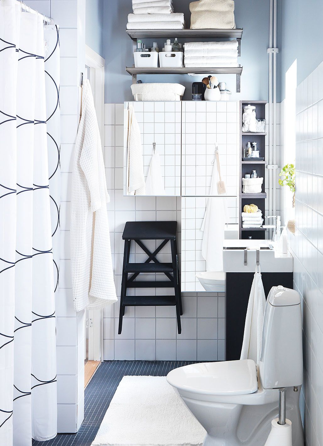 Na maximálně využité stěně v menší koupelně jsou zrcadlové skříňky, police a židlička. Pod umyvadlem je úložná skříňka.