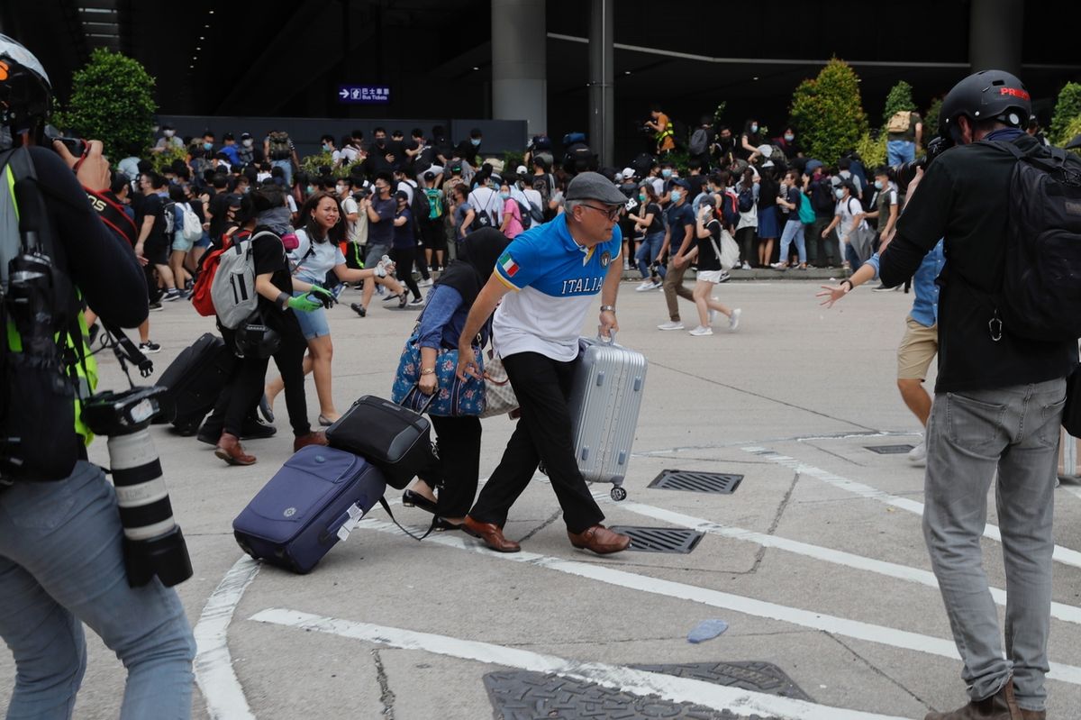 Cestující se snaží dostal pryč z letiště, kam se v neděli přemístili demonstranti. 