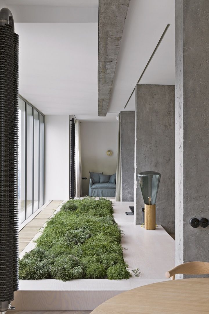 Ruch velkoměsta versus přírodní elementy jsou otisknuty do interiéru prostřednictvím přiznaných betonových panelů a nestandardní interiérové zahrady.