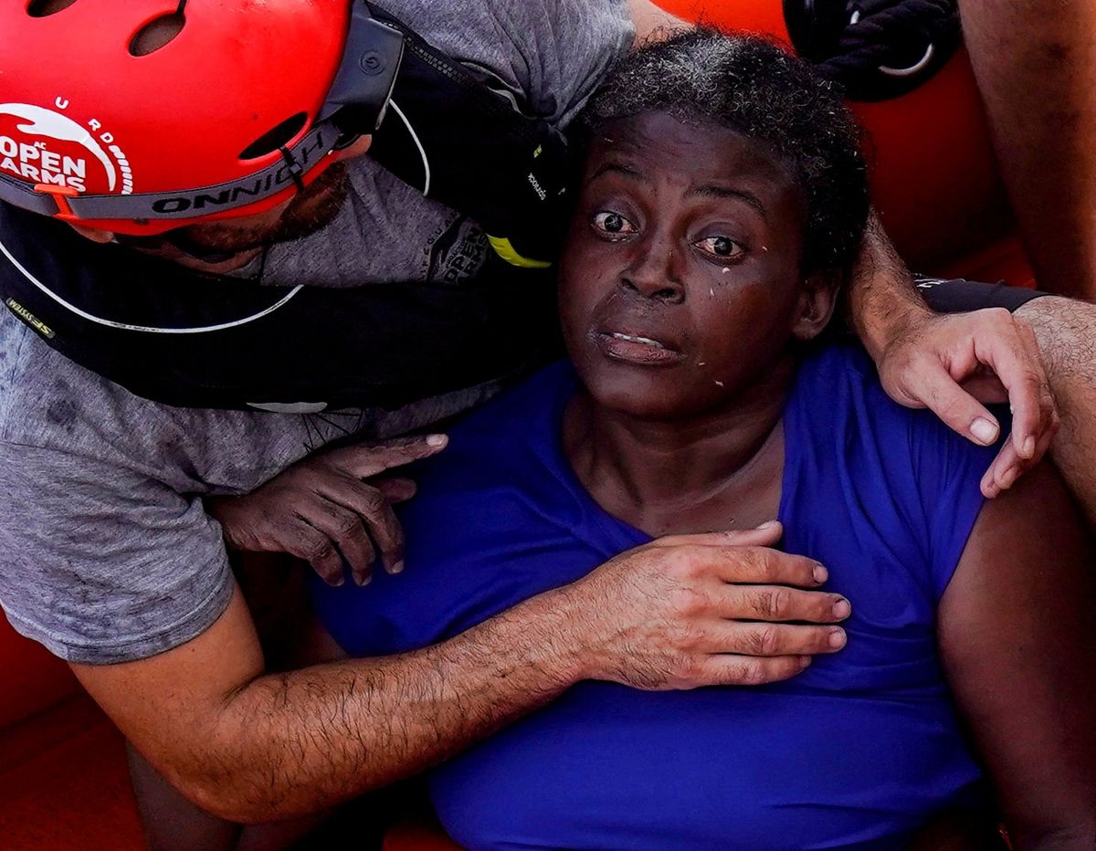 Muž pracující pod záštitou organizace Open Arms uklidňuje ženu po záchraně z uprchlického člunu.