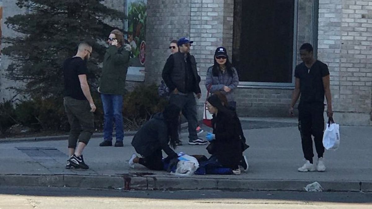 Chodci pomáhají jedné z obětí, kterou srazila dodávka v kanadském Torontu.