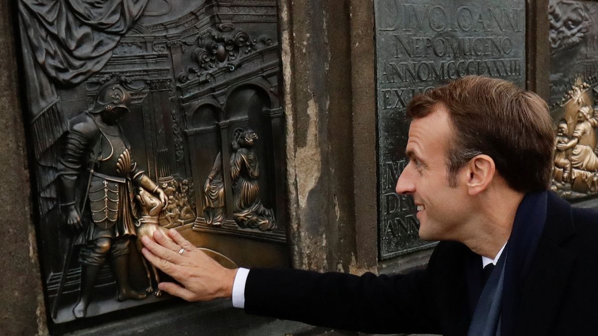 Francouzský prezident Emmanuel Macron se dotýká bronzového reliéfu Václava IV. s loveckým psem na soklu sochy sv. Jana Nepomuckého na Karlově mostě v Praze.