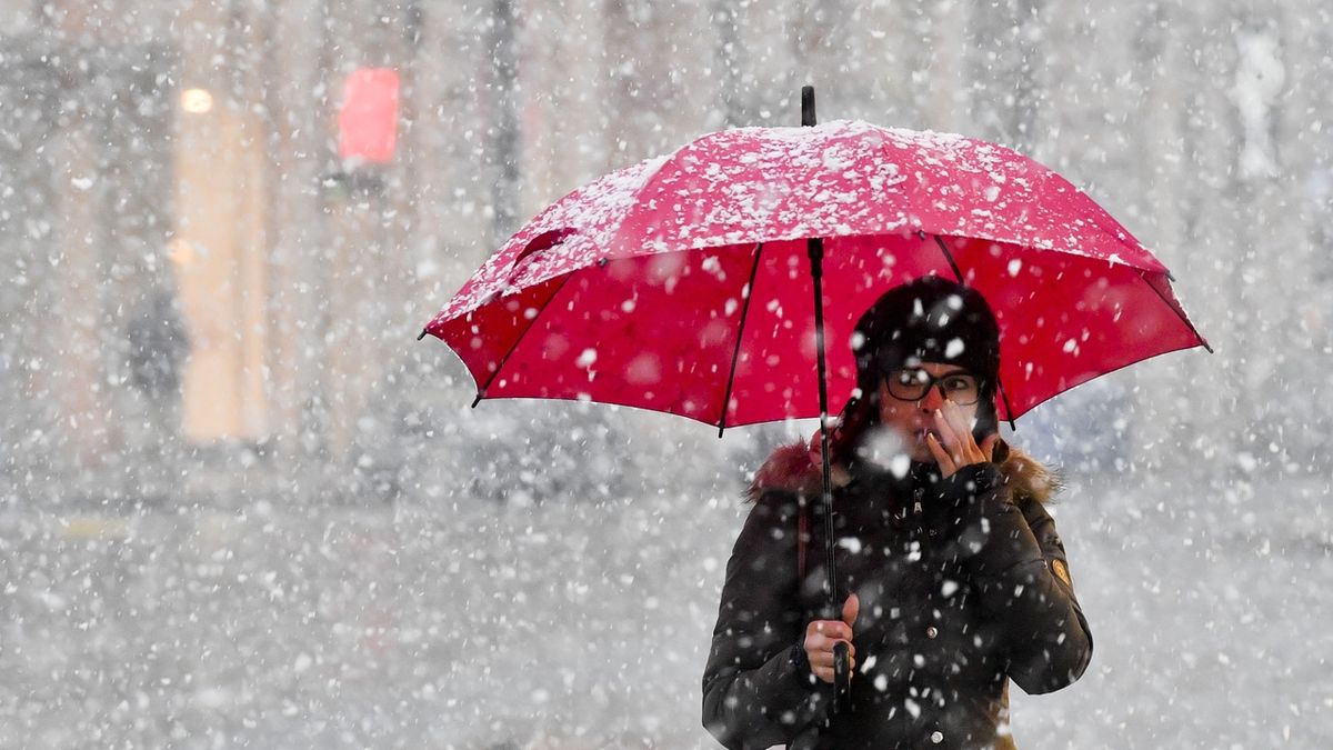 Žena s deštníkem ve sněhové přeháňce, která se 2. ledna přehnala nad Václavským náměstím v Praze.