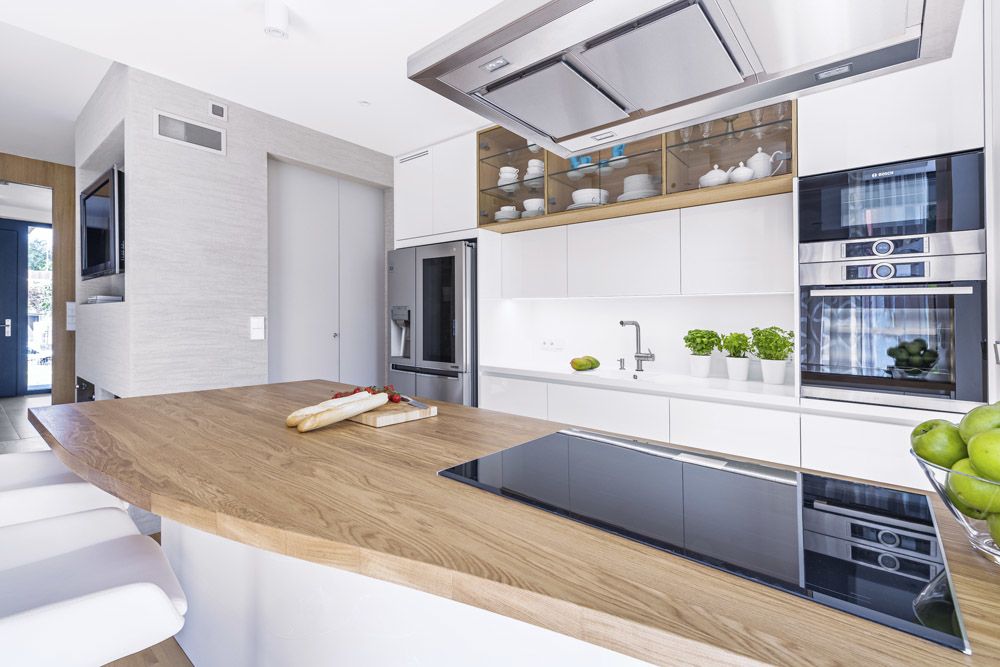 Bílá kuchyň z lakované MDF desky je vybavená spotřebiči značky Bosch.
