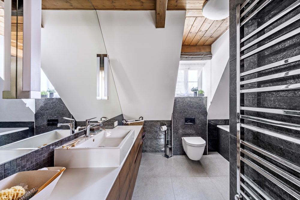 Koupelna v patře zahrnuje akrylátovou vanu (Riho) a klozet (Duravit). Stěna za mořenou dubovou skříňkou s umyvadlem Vero (Duravit) je obložená zrcadlem. Odrazem opticky zvětšuje místnost.