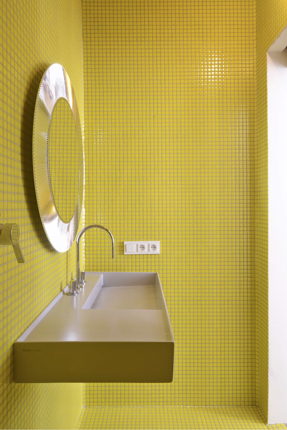 Drobná mozaika ve žluté barvě prostor opticky zvětšuje.