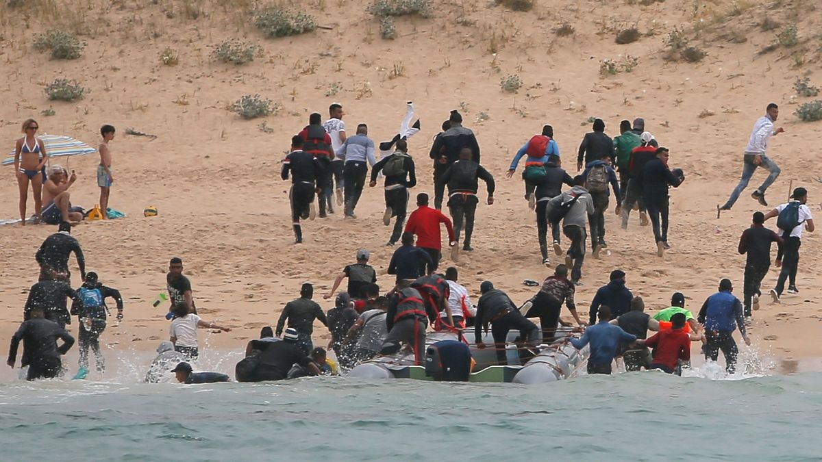 Migranti prchali přes pláž do blízkého lesa.

