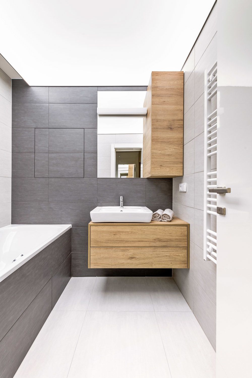 Architekt i investor vyzdvihují jedno rafinované řešení v rámci koupelny, jde o celoplošné osvícení stropu (Vecta), které bylo náročnější co do provedení. Velkoformátový obklad v koupelně v zemité barvě doplňuje dýhovaný koupelnový nábytek na míru.