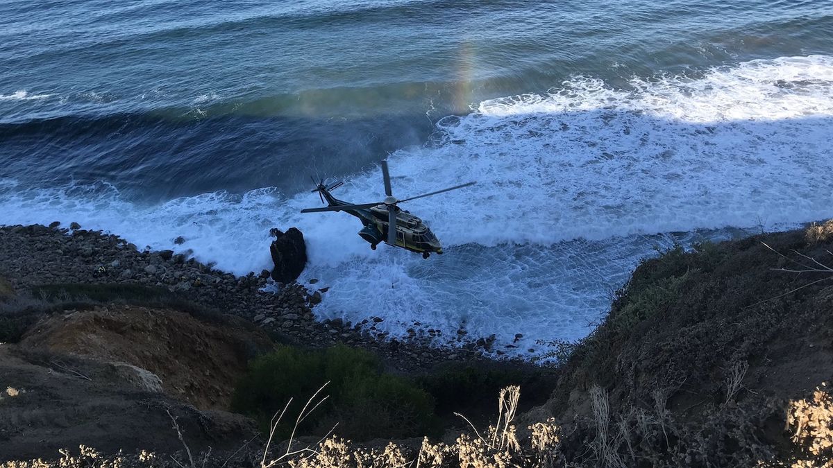 Vrtulník zachraňuje ženu, která spadla z útesu.