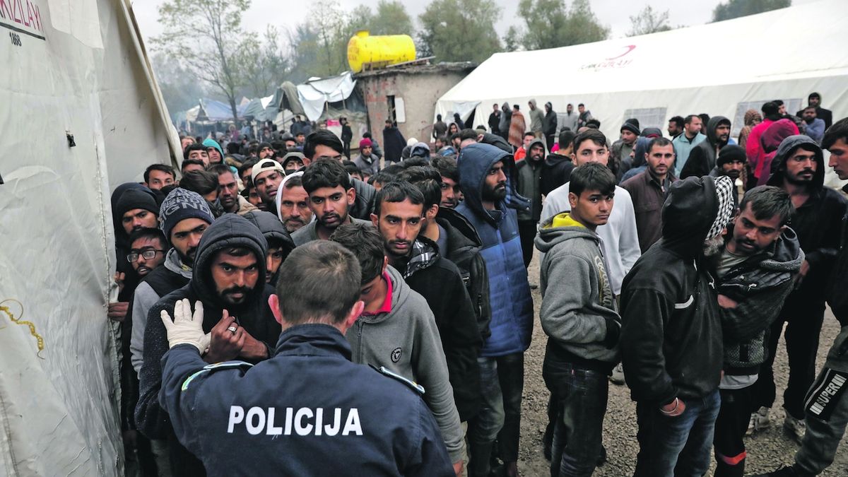 Policista se snaží seřadit migranty, kteří čekají na darované zimní oblečení v bosenském táboře Vučjak.