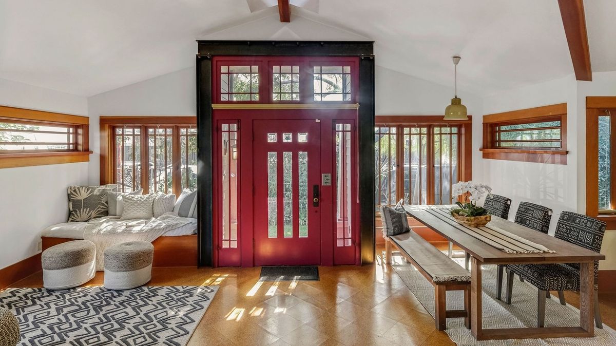 Vstupní dveře do předního bungalovu mají jasnou červenou barvu. Vzhledem jsou ale hezky sjednoceny s dřevěnými okny.