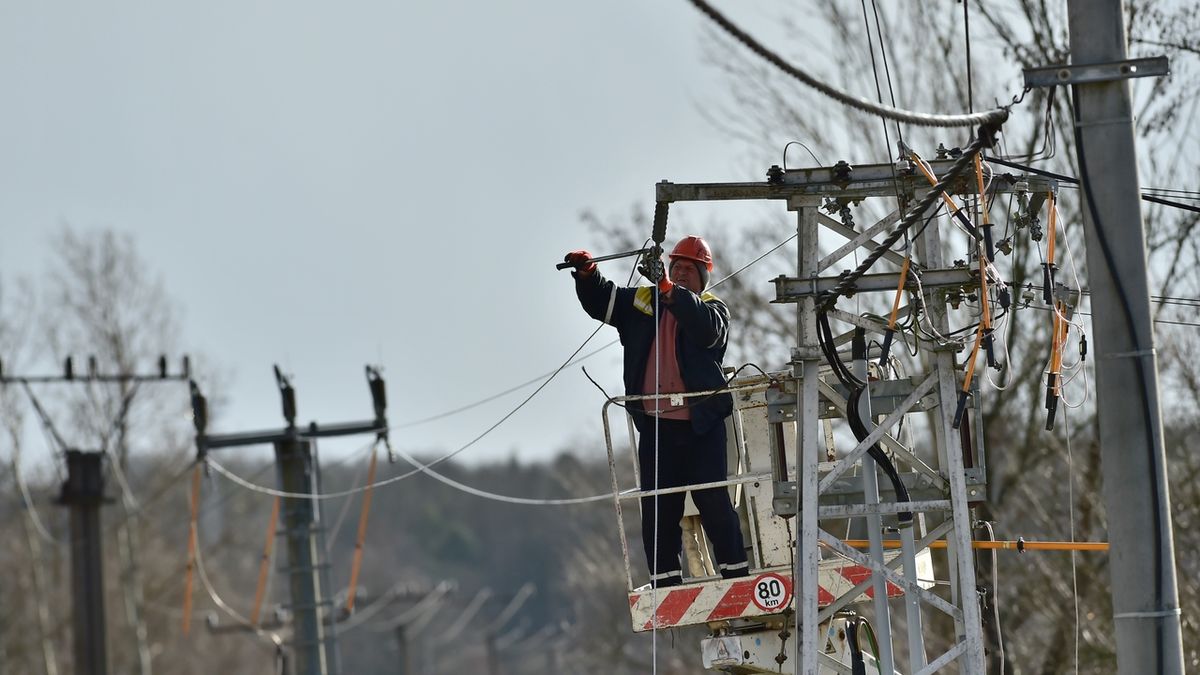 Pracovník energetické společnosti opravuje zpřetrhané vedení v Myšenci na Písecku.