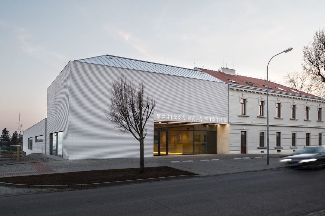 Vítězná stavba haly v Modřicích respektuje výšku okolní zástavby. Předprostor budovy tvoří plocha dlážděná drobnou žulovou mozaikou různých odstínů, která zdůrazňuje význam nové budovy.