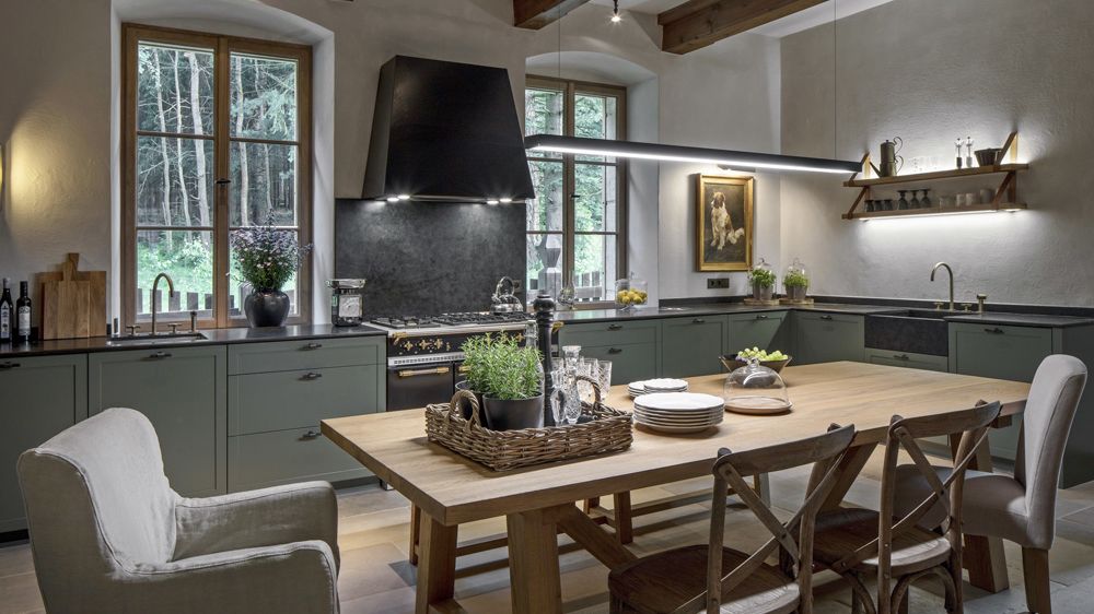 Lomený odstín zelenošedé barvy staví na odiv na míru zhotovená kuchyňská sestava dubového nábytku doplněná zinkovanými spoji. 