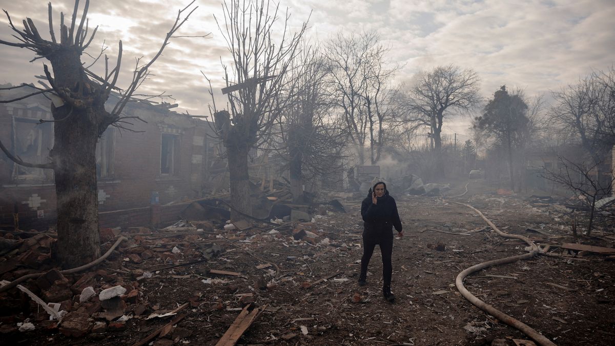 Místní obyvatelka prochází zničeným předměstím Charkova.