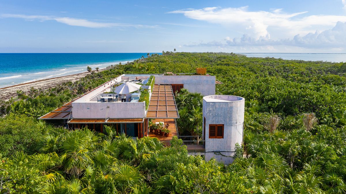 Betonový dům stojí na pobřeží moře, v husté palmové džungli.