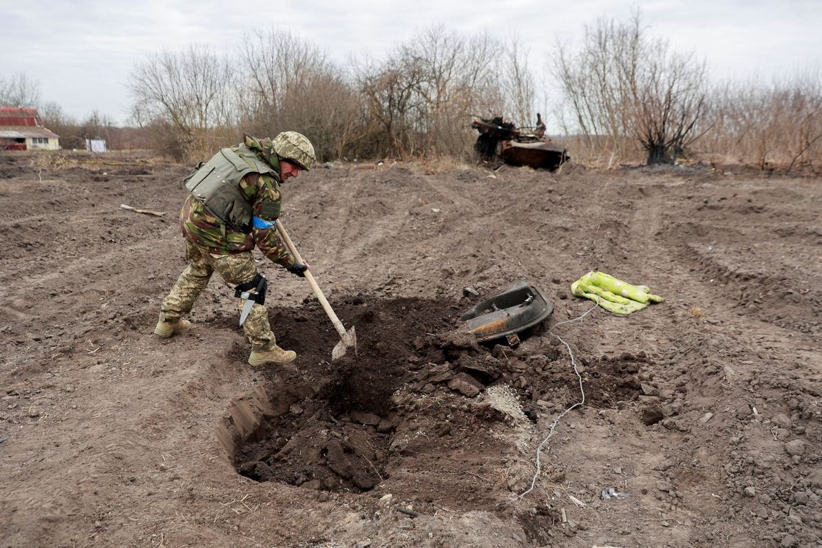 Ukrajinský voják pohřbívá pozůstatky padlého Rusa v Lukjanivce 