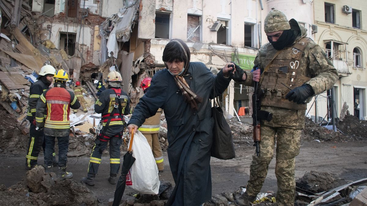 Příslušník ukrajinské domobrany pomáhá ženě přejít ulici v Charkově