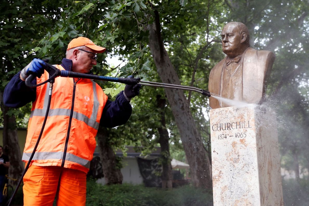 Pracovník úklidové firmy čistí posprejovaný pomník Winstona Churchilla v Budapešti