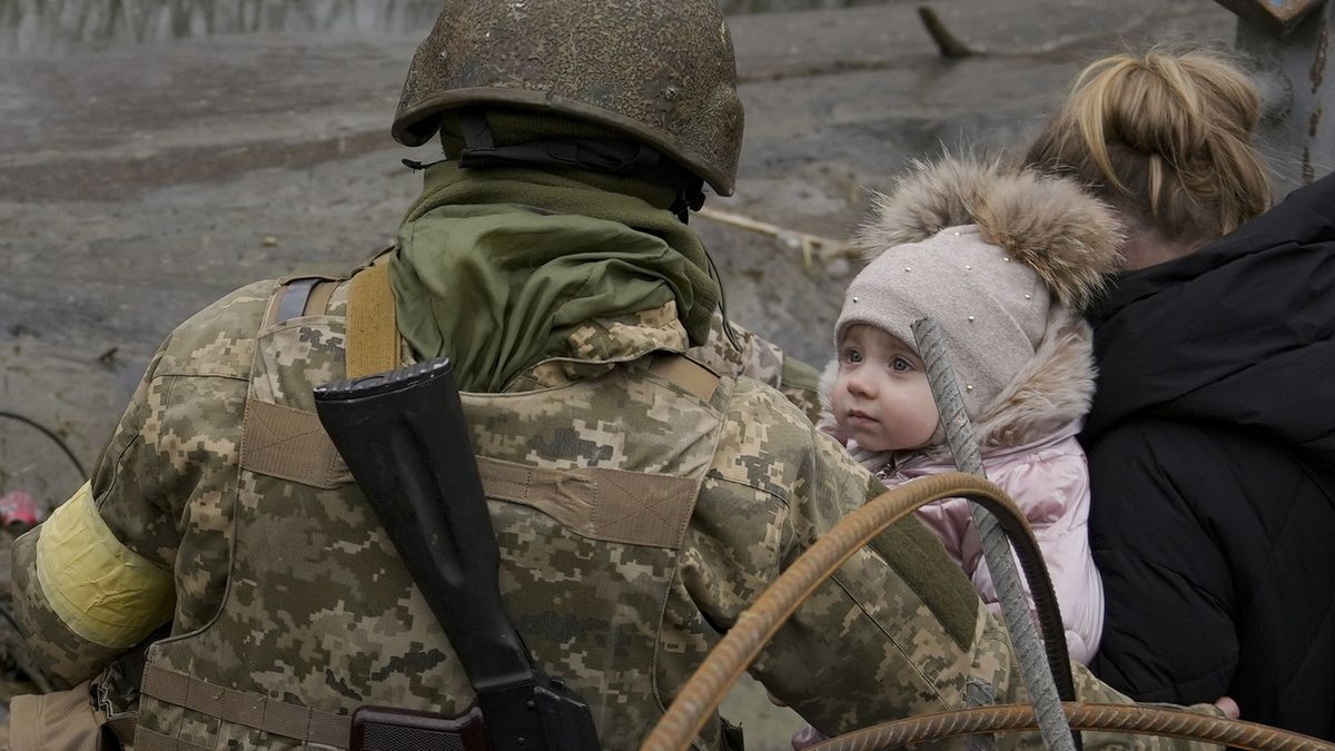 Holčička se dívá na ukrajinského vojáka, zatímco ji evakuuje z Irpině