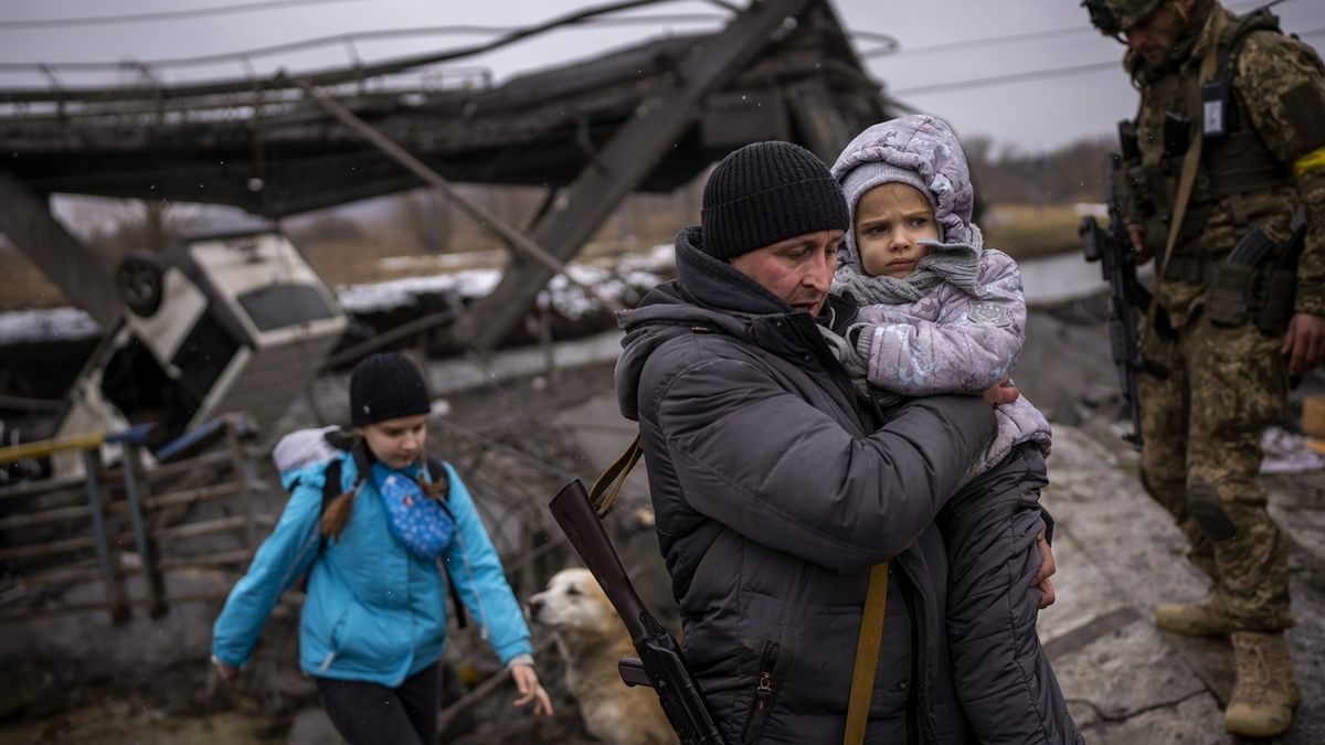 Místní milicionář pomáhá evakuovat rodinu po útoku dělostřelectva na předměstí Kyjeva