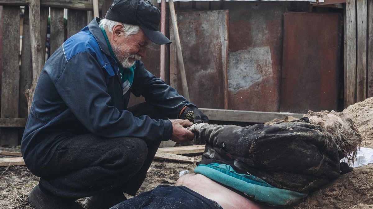 Otec truchlí nad mrtvým tělem svého syna, jenž se stal obětí masakru ve městě Buča. 