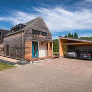 Podlouhlá garáž s pultovou střechou doplňuje dům a odděluje obytnou zahradu od zástavby. Auta parkují spíše pod zastřešením, uzavřená garáž slouží jako dílna a sklad