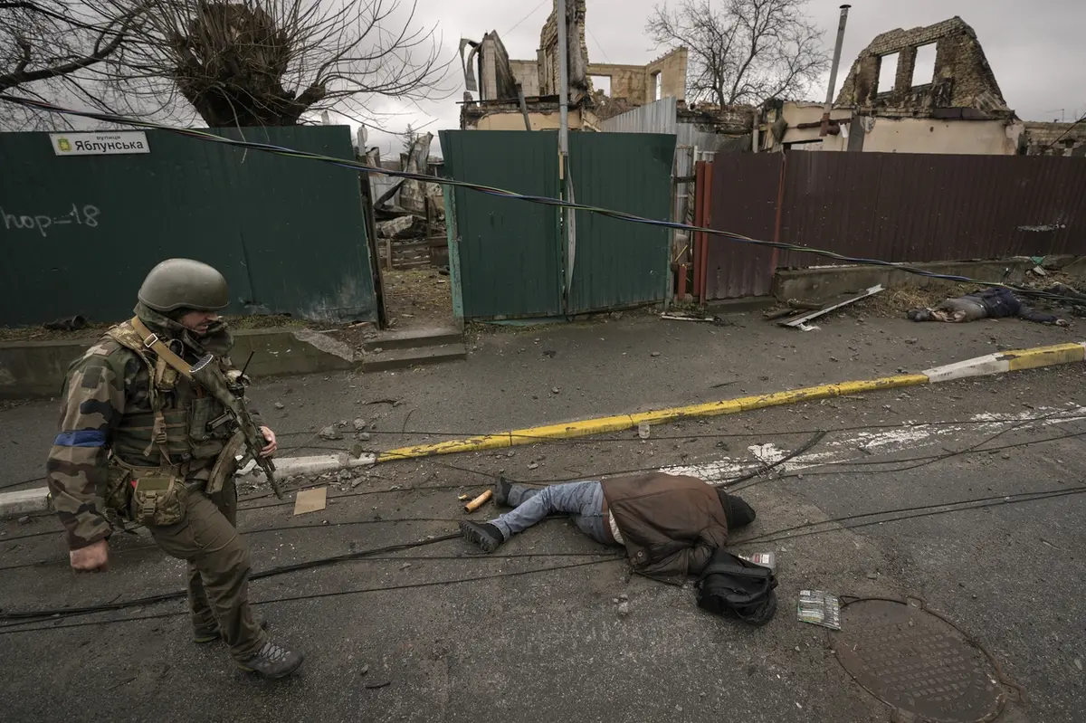 Ukrajinský voják prochází kolem jednoho ze zabitých civilistů v Buči.