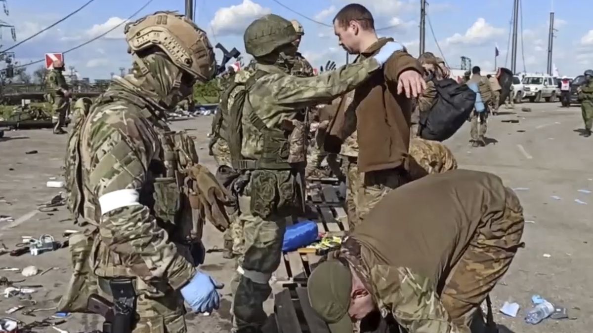 Ruští vojáci prohledávají ukrajinské bojovníky z oceláren Azovstal v okupovaném Mariupolu na fotografii poskytnuté ruským ministerstvem obrany