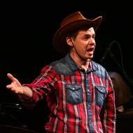 Petr Macháček v kovbojském kostýmu zpívá Krajinu posedlou tmou