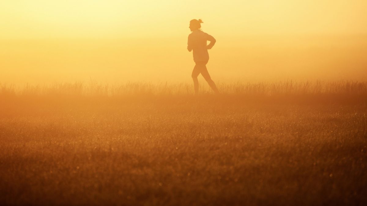 Žena sportuje při východu slunce.