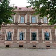 Pohled na opravenou budovu bývalé opatské rezidence, jejíž zdi jsou sestavené z ohromných kamenných bloků.